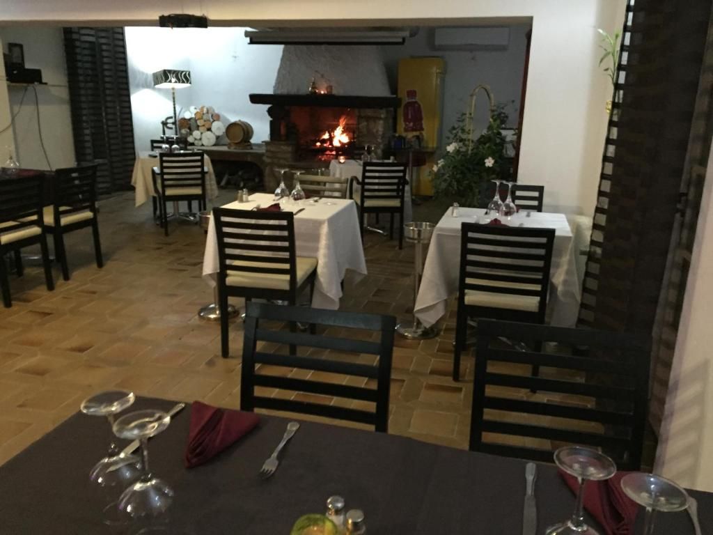 A restaurant with tables set for dining, a fireplace, and a view of the outside.