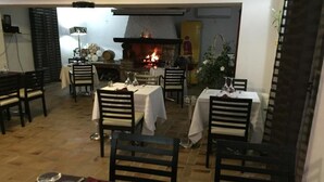 Ein Restaurant mit gedeckten Tischen, einem Kamin und Blick ins Freie.