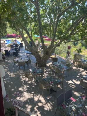 An outdoor patio area with tables and chairs, surrounded by trees.