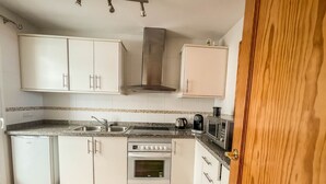 A compact kitchen with white cabinets, a built-in oven, a microwave, and a coffee maker. - Charming Townhouse with Sea Views & Pool in Altea (Altea)