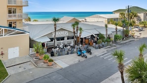 A beachfront building with a sign reading "Schooners", a beach club, and a parking area with a blue motorcycle.