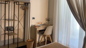A hotel room with a bed, a desk with a chair, a small table with glasses and a vase, a wardrobe, and an air conditioning unit. - ar.b&b nel cuore di napoli (Naples)