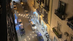 A nighttime view of a narrow street lined with multi-story buildings, featuring balconies and ground-floor shops. - ar.b&b nel cuore di napoli (Naples)
