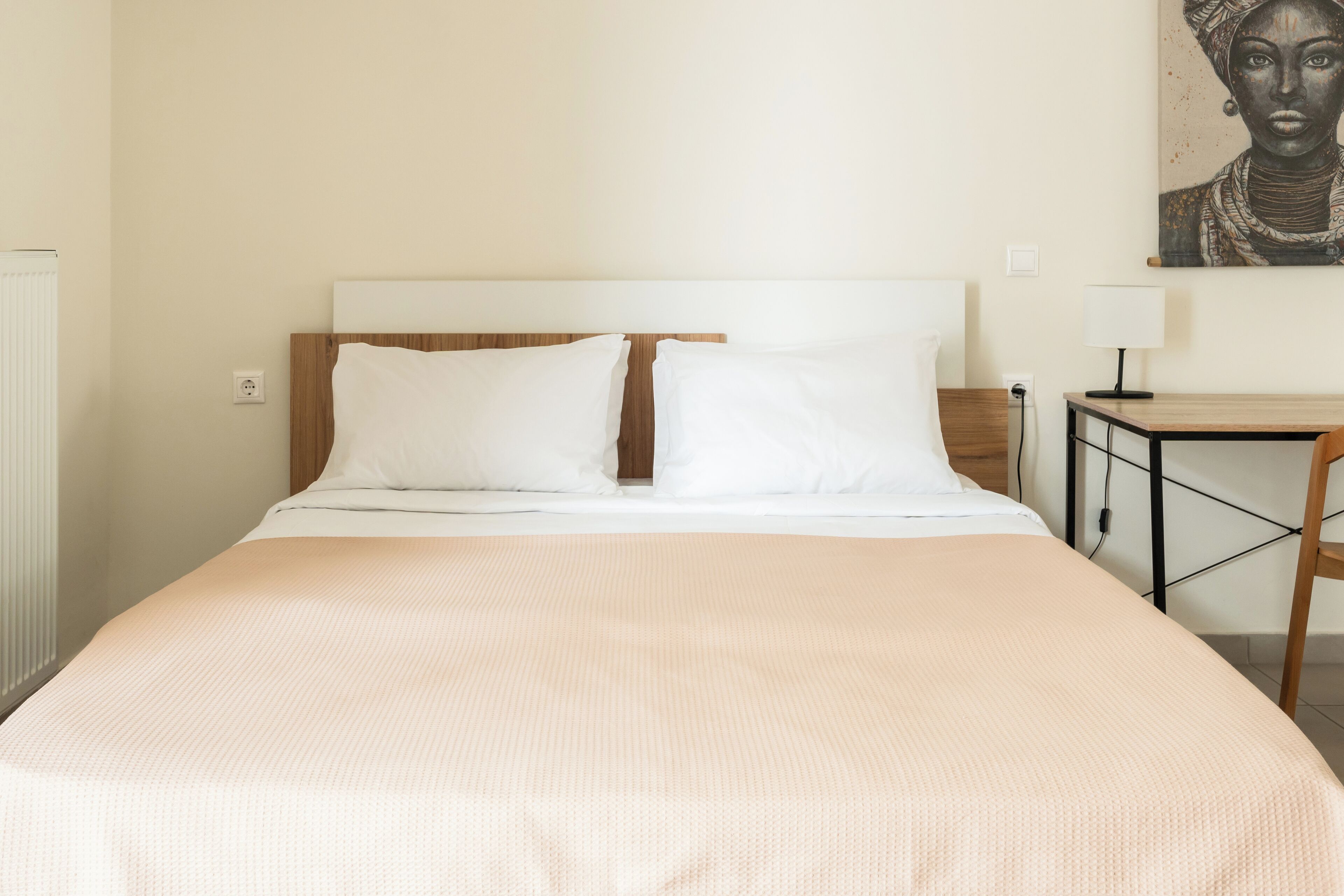 A neatly made bed with white linens, a wooden headboard, and a small bedside table with a lamp.