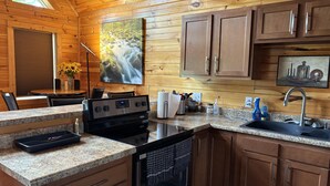 Una cocina moderna con encimeras de granito, electrodomésticos de acero inoxidable, armarios de madera y un amplio ventanal con vistas a una cascada.