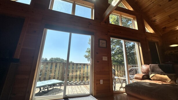 Una cabaña de madera con un amplio ventanal corredero que da a una terraza exterior.