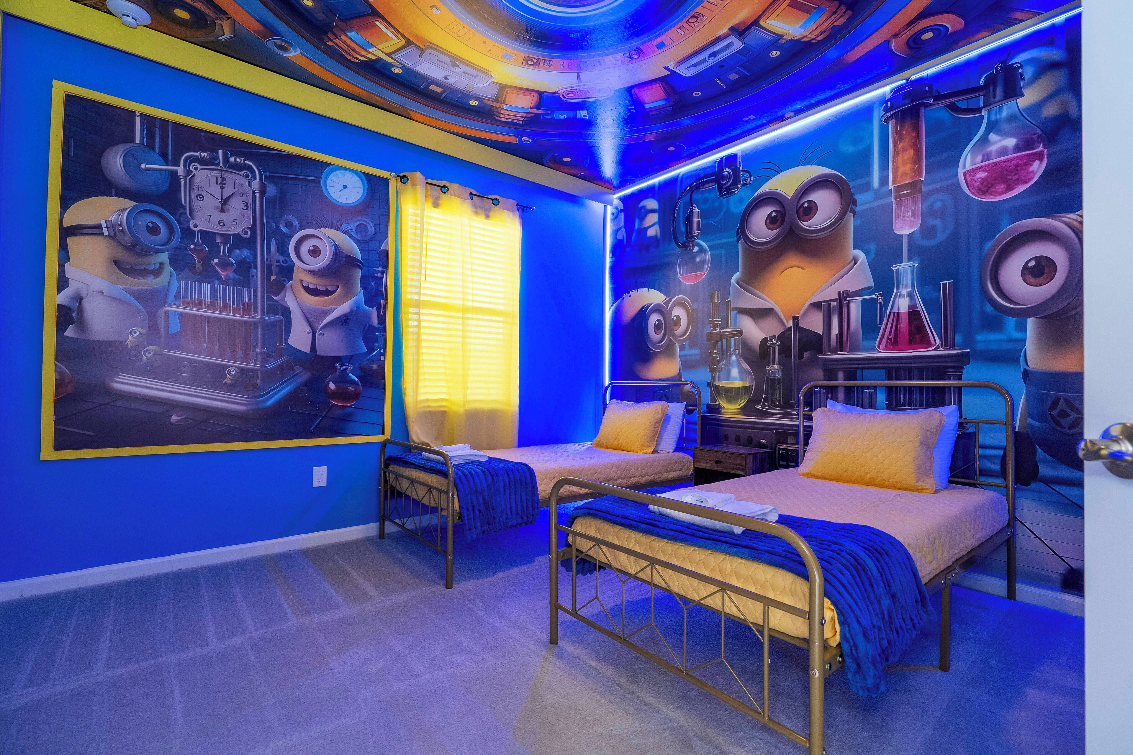 A bedroom with two beds, a large poster of minions, and a ceiling with a circular design.