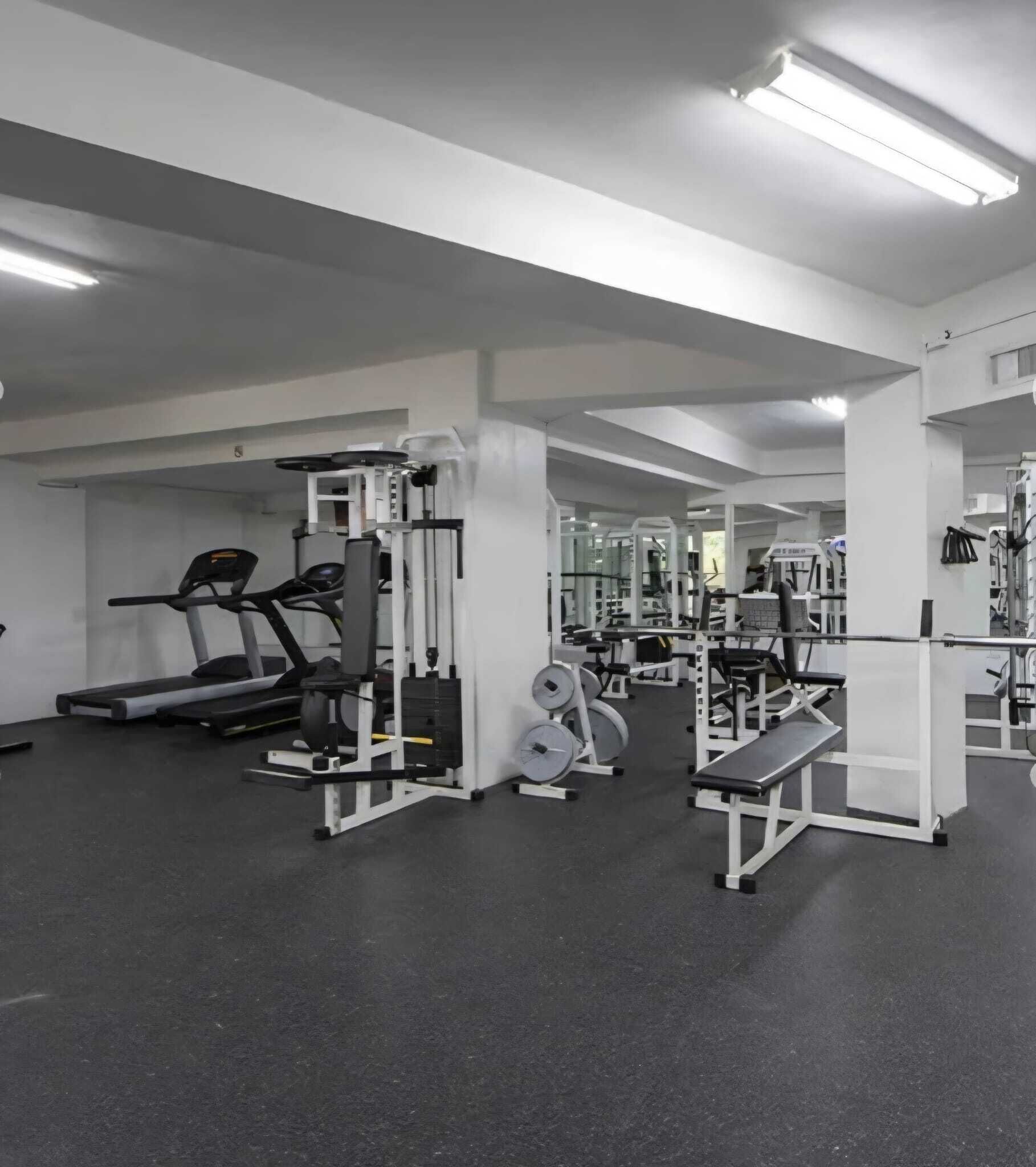 A gym with treadmills, weight machines, and benches.