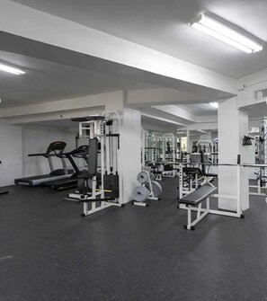 Un gimnasio con cintas de correr, máquinas de pesas y bancos.
