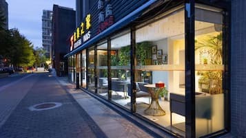 A restaurant with outdoor seating, large windows, and a visible interior with tables and chairs.