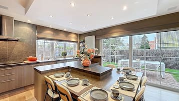 Een moderne keuken met een centraal kookeiland, grote ramen en uitzicht op de achtertuin.