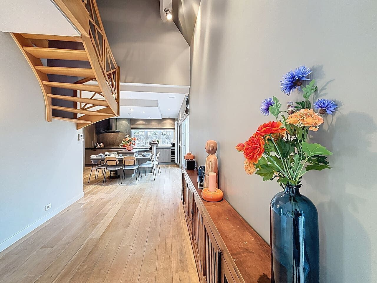 Un hall d’entrée spacieux, doté d’un plancher en bois, mène à une cuisine équipée d’appareils électroménagers modernes et comprenant un coin repas.