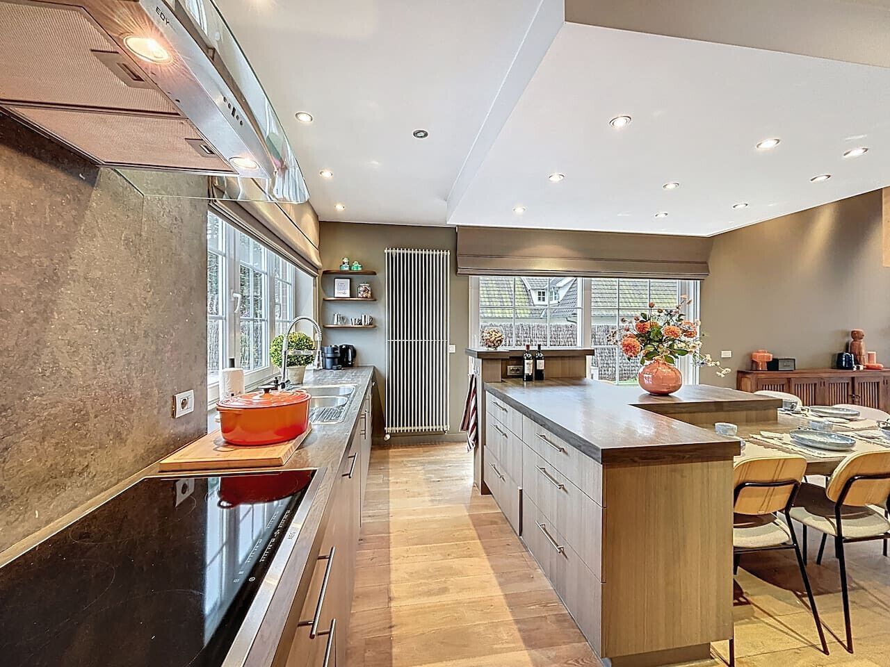 Een moderne keuken met een centraal eiland, houten keukenkastjes en een groot raam voor natuurlijk licht.