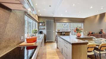 Een moderne keuken met een centraal eiland, houten keukenkastjes en een groot raam voor natuurlijk licht.