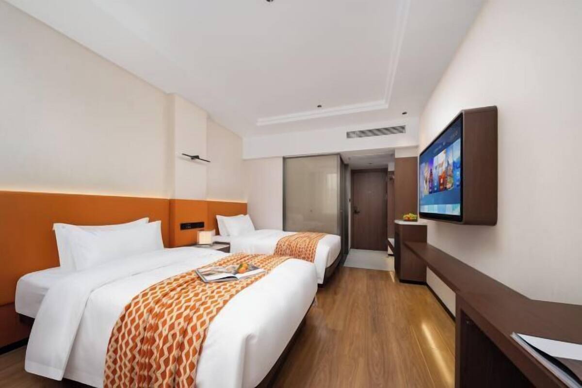Een hotelkamer met twee bedden, een televisie en een bureau.