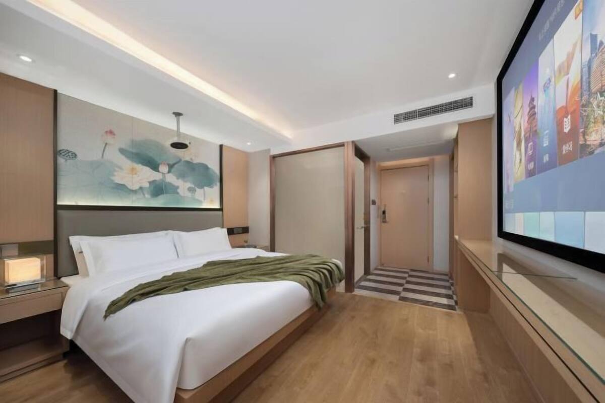 Een moderne hotelkamer met een groot bed, een flatscreen televisie en een schilderij aan de muur.