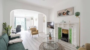 A modern living room with a fireplace, a dining area, and a sofa. - Spacious modern apartment in South Croydon (South Croydon)