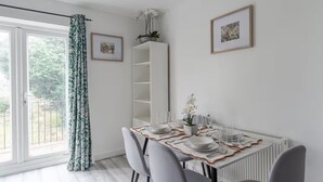 A dining area with a table set for four, a white cabinet, and a radiator. - Spacious modern apartment in South Croydon (South Croydon)