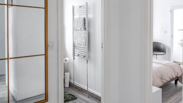 A modern bedroom with a large mirror, a bed, and a walk-in closet. - Spacious modern apartment in South Croydon (South Croydon)