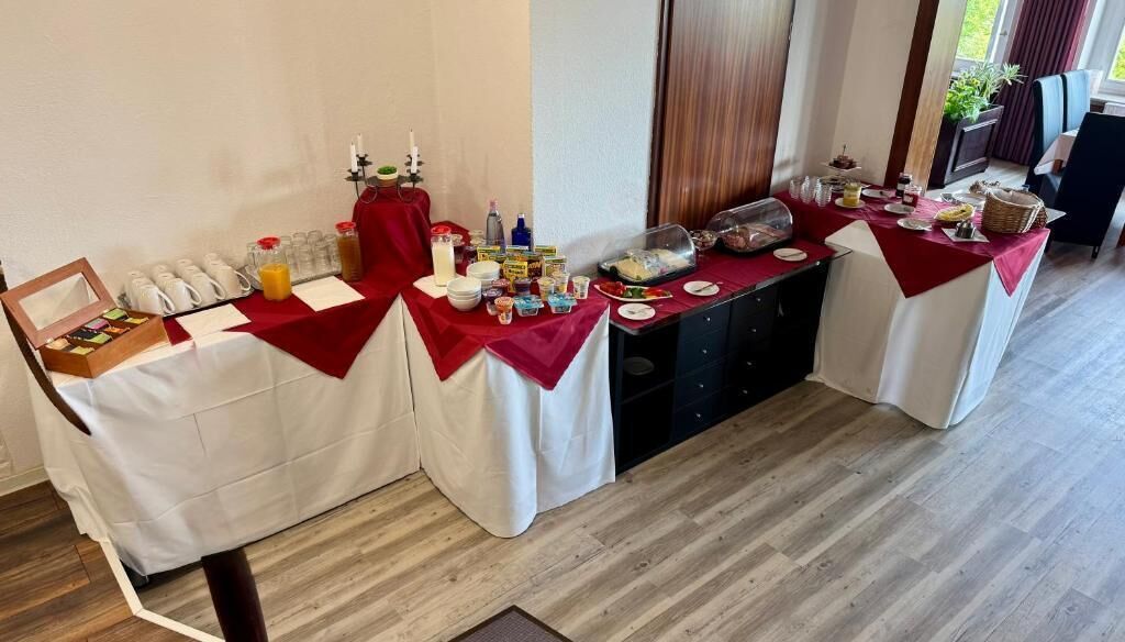 Montaje de un bufé de desayuno con diversas opciones de comida y bebidas, un espejo y una pequeña caja de regalo.