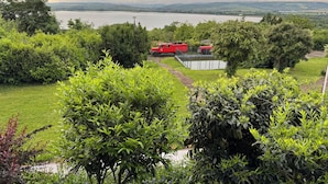 A lush green landscape with a lake, trees, and a red building in the distance. - Barbarossa Hotel Kelbra (Kelbra)