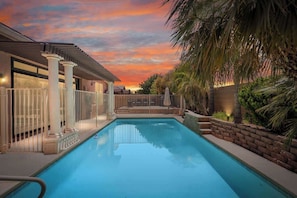 Ein Pool mit einer Pergola und Palmen, umgeben von einem Zaun.