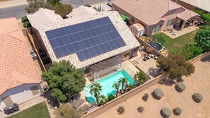 Ein Wohnhaus mit Schwimmbad, Solaranlage und überdachter Terrasse.