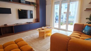 Ein modernes Wohnzimmer mit Flachbildfernseher, einem Holztischelement, einem Couchtisch und einer Couch.