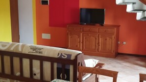 Un coin repas avec une table dressée pour quatre personnes, des chaises en bois, un banc et un escalier en arrière-plan.