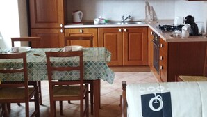 Une cuisine avec des meubles de rangement en bois, une table à manger avec des chaises et un canapé.