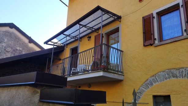 Un bâtiment jaune doté d’un balcon avec une rambarde en métal et une paroi en verre.
