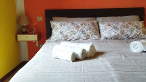 Un lit bien fait avec deux oreillers, une table de chevet avec une lampe et une prise électrique au mur.