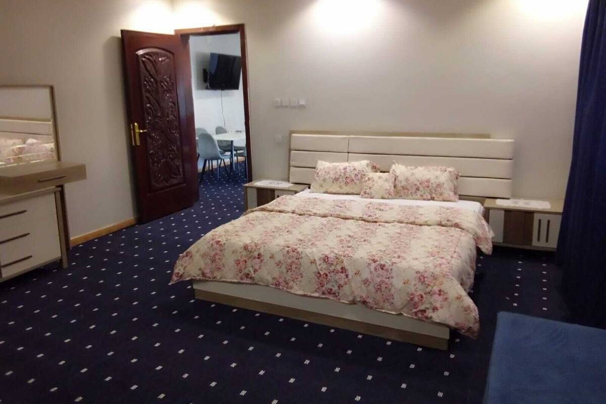 A bedroom with a bed, bedside tables, a desk, and a chair.