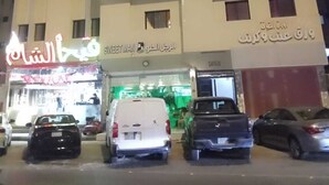 Un edificio de varios pisos con un letrero de Sweetman y otro de restaurante. Hay varios coches estacionados adelante.