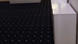 Una habitación de hotel con cama, armario, espejo y una pequeña mesa blanca.