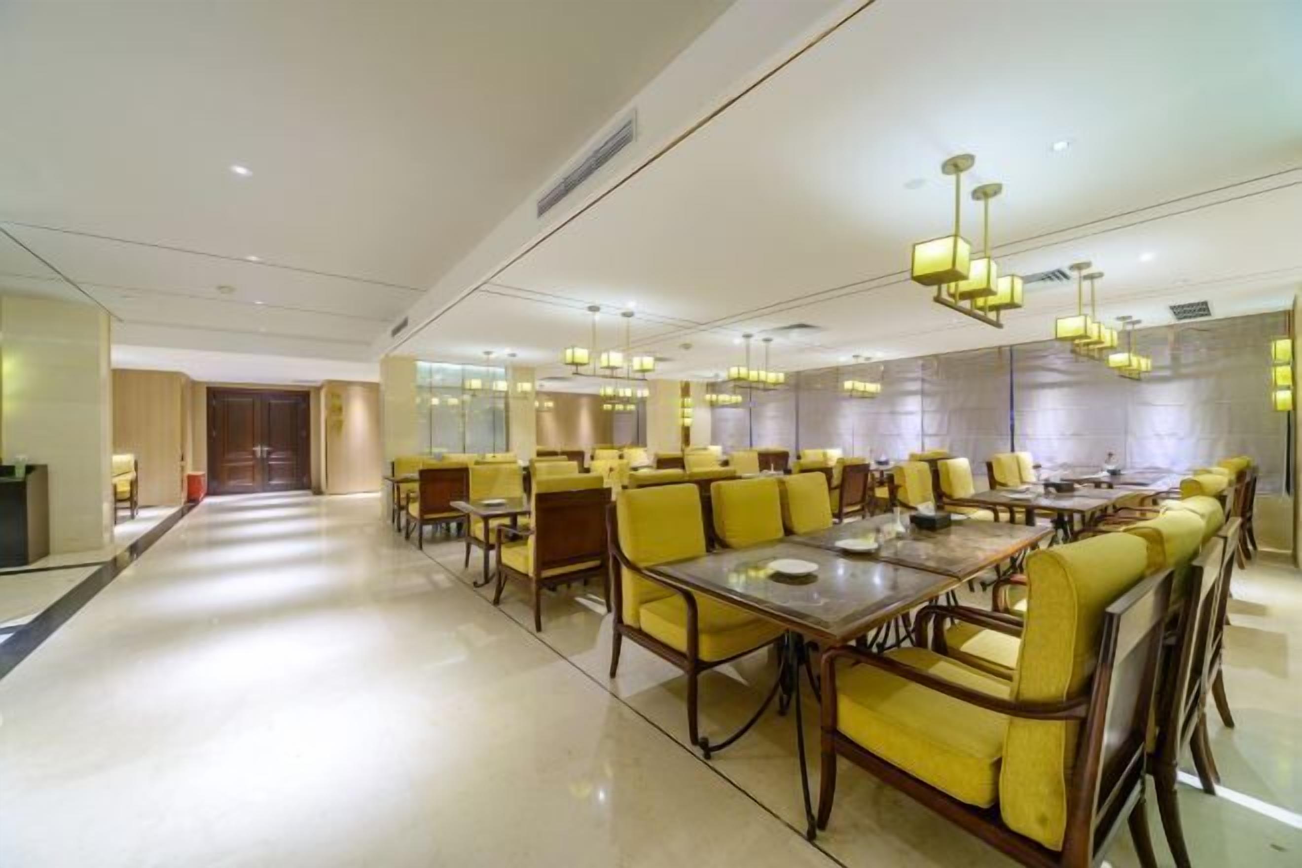 A spacious dining area with yellow chairs and tables, modern lighting fixtures, and a clean, polished floor.