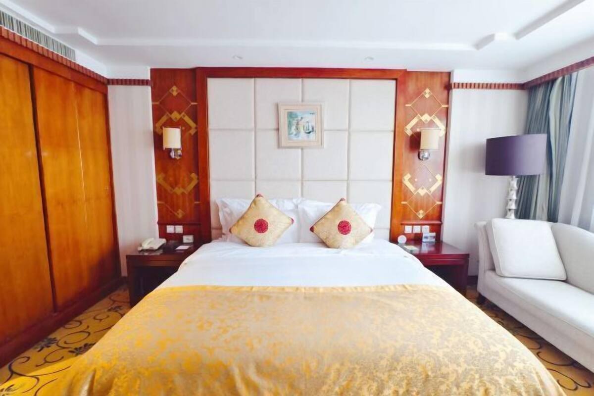 Een hotelkamer met een groot bed, een bank, een nachtkastje en een tv aan de muur.
