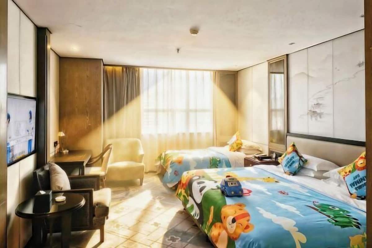 Een hotelkamer met twee bedden, een bureau, een stoel en een televisie.
