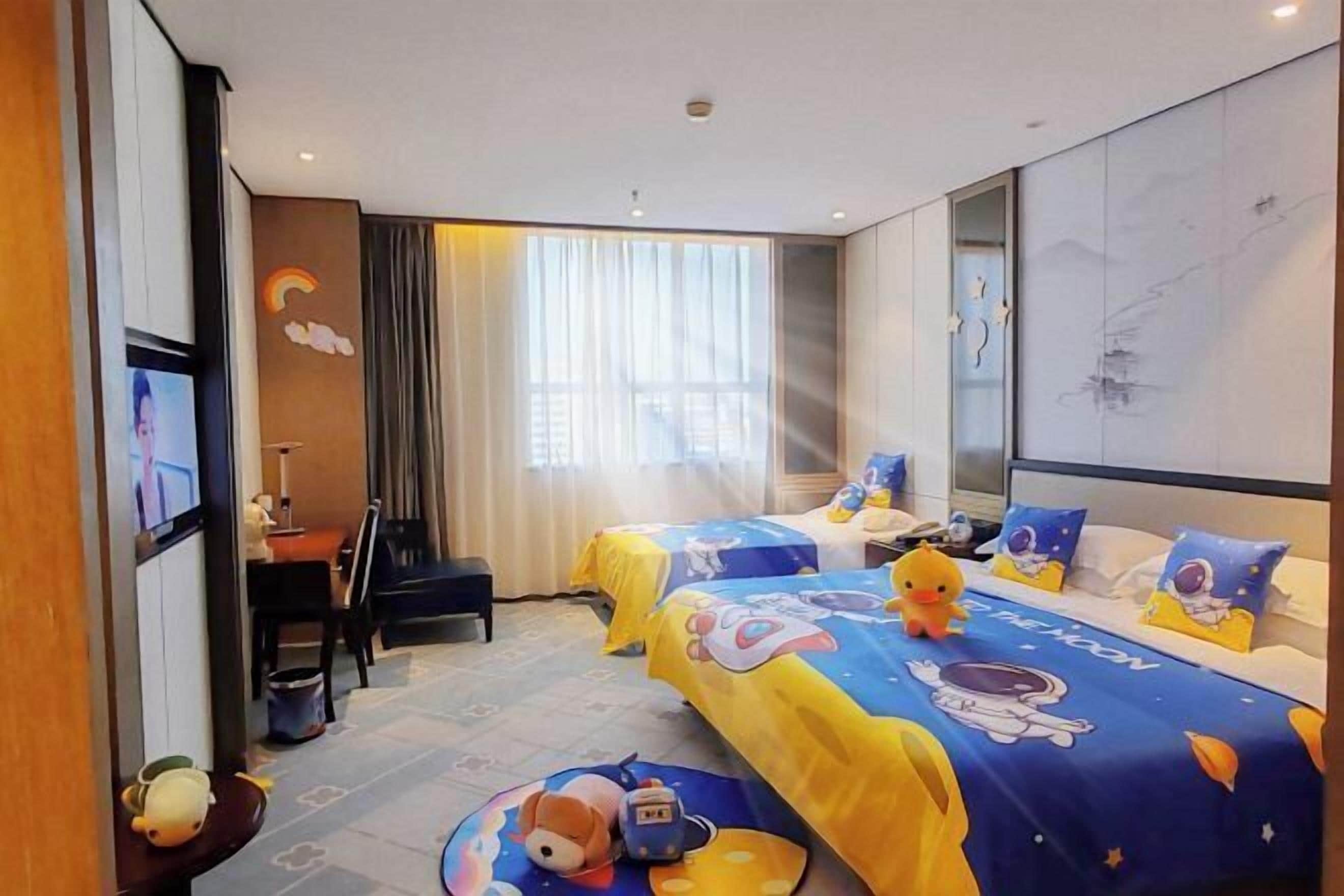 Une chambre d’hôtel avec deux lits, une télévision, un bureau et une grande fenêtre.