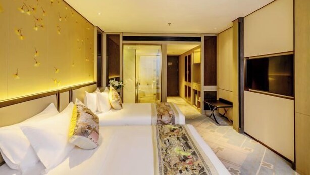 Ein modernes Hotelzimmer mit zwei Betten, einem großen Spiegel und einem Fernseher.