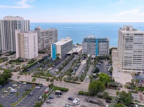 A high-rise building complex with multiple parking lots and a view of the ocean.