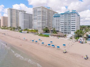 A beachfront hotel with multiple high-rise buildings, a sandy beach with umbrellas, and a pool area. - Ocean Manor 1BR - Beachfront, Pool & Tiki Bar (Fort Lauderdale)