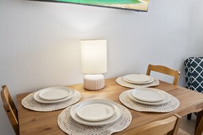 A wooden dining table with white plates and a white table lamp.