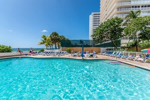 A pool area with lounge chairs and a view of the ocean. - Ocean Manor 1BR - Beachfront, Pool & Tiki Bar (Fort Lauderdale)