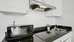 Uma cozinha moderna com micro-ondas embutido, pia de aço inoxidável e uma pequena planta em vaso.