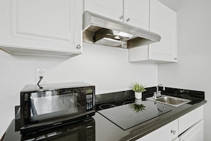 A modern kitchen with a built-in microwave, a stainless steel sink, and a small potted plant. - Ocean Manor 1BR - Beachfront, Pool & Tiki Bar (Fort Lauderdale)
