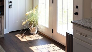 Une pièce avec un plancher en bois, une porte blanche et une fenêtre donnant sur l’extérieur.