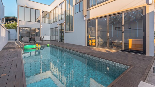 A modern house with a swimming pool, large windows, and a deck area.
