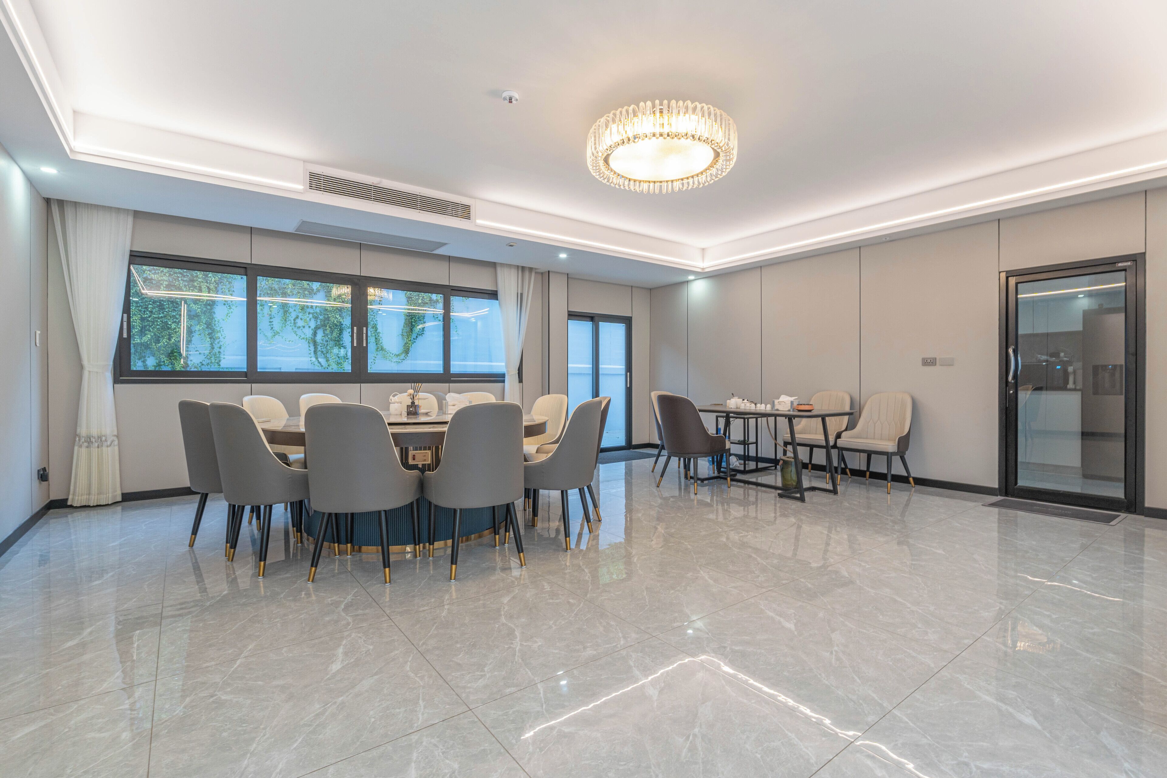 A spacious conference room with a large table and chairs, large windows, and a chandelier.