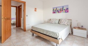 Une chambre à coucher avec un lit, une table de chevet, une commode et un tableau accroché au mur.